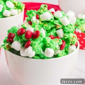 Grinch-themed popcorn drizzled with green candy melts and red heart sprinkles, ideal for holiday movie nights.