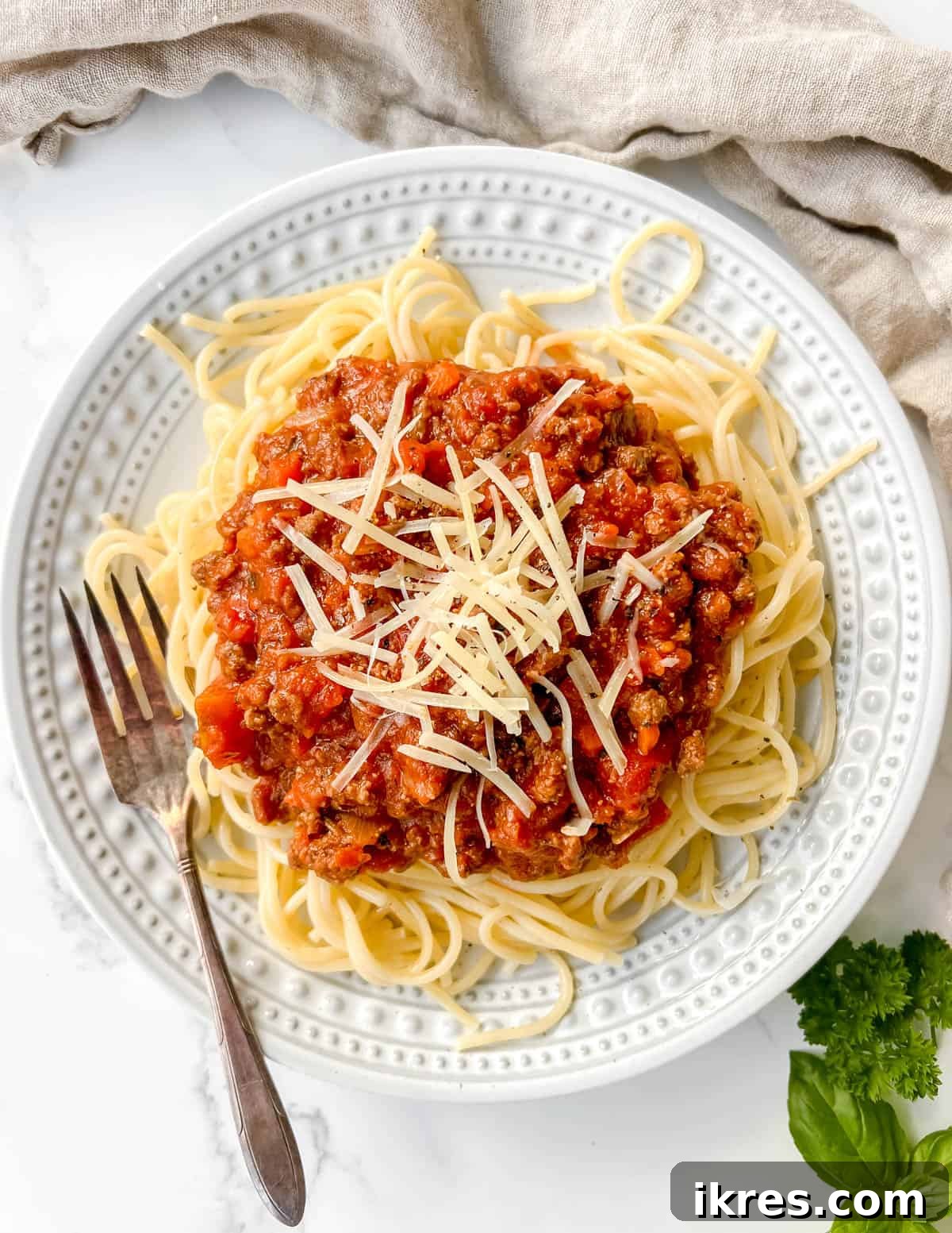Close-up shot of rich bison meat sauce generously spooned over a tangle of spaghetti, ready to be served.