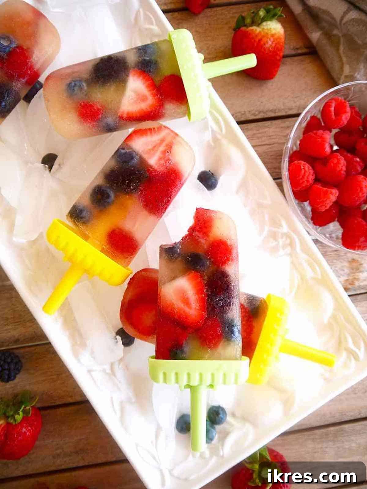 A homemade apple juice popsicle with a bite taken out, showing the frozen berries inside.