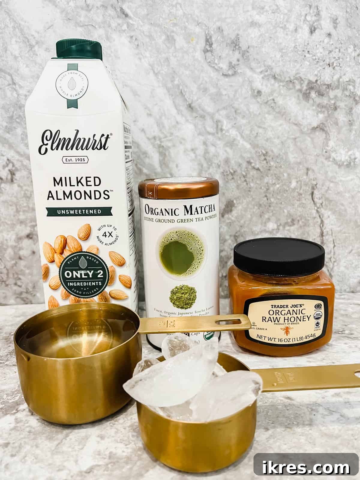 Creamy Vegan Iced Almond Matcha Latte 4 All the fresh ingredients laid out: matcha powder, hot water, honey, almond milk, and ice cubes.
