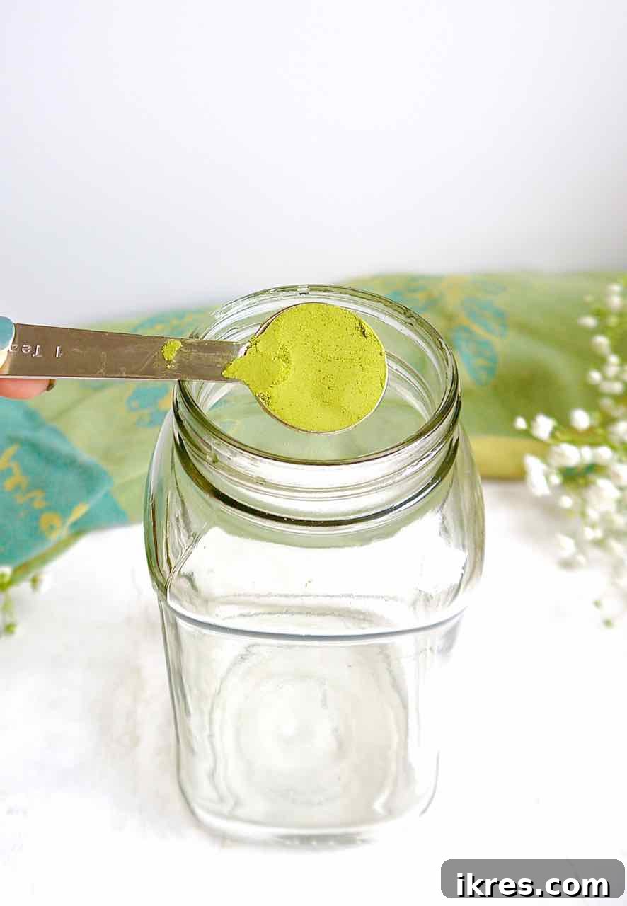 Creamy Vegan Iced Almond Matcha Latte 5 A scoop of ceremonial grade matcha powder being added to a mason jar.