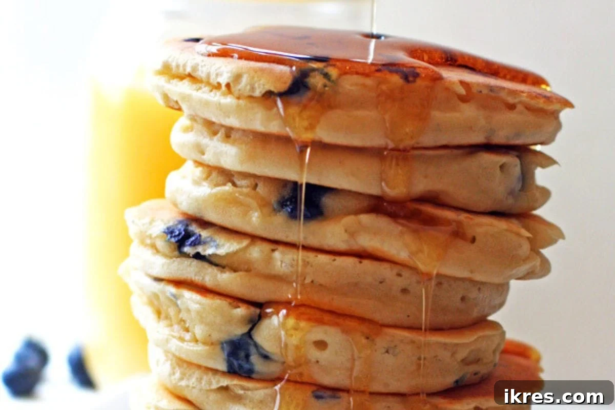 Ultimate Brunch Piled High Pancakes Waffles and Delicious Sauces 3 A vibrant stack of fluffy blueberry pancakes drenched in golden maple syrup, ready to be enjoyed for breakfast or brunch.