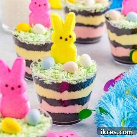 Easter dirt cups composed of Oreo dirt crumbs, layers of creamy pudding, and adorned with edible Easter decorations, presented as the cutest and easiest Easter treat.