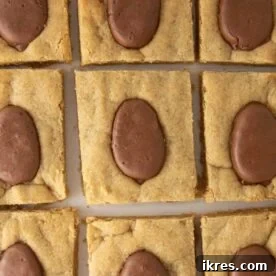 Soft, chewy peanut butter cookie bars infused with Reese's Eggs, showcased as a perfect and quick Easter dessert that can be made in under 30 minutes in a 9x13 pan.
