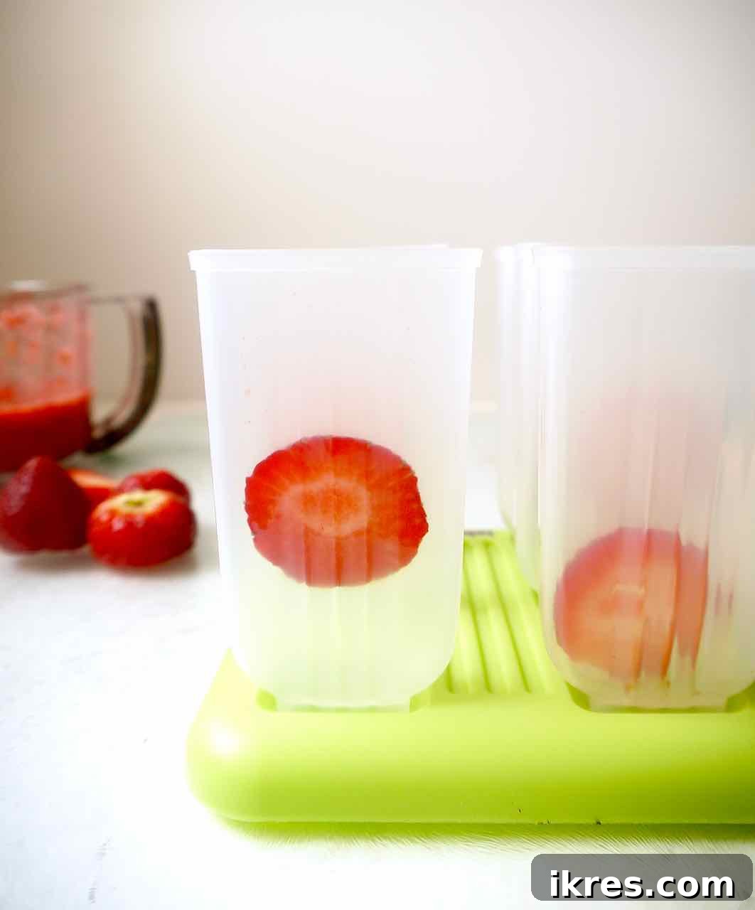 Strawberry Matcha Fusion Pops 4 Fresh strawberry slices carefully placed inside a popsicle mold before adding any liquid.