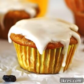 Moist and delicious Carrot Cake Muffins with a sweet glaze, displayed on a white table alongside a glass of orange juice, perfect for breakfast, brunch, or dessert during spring celebrations like Easter or Mother's Day.