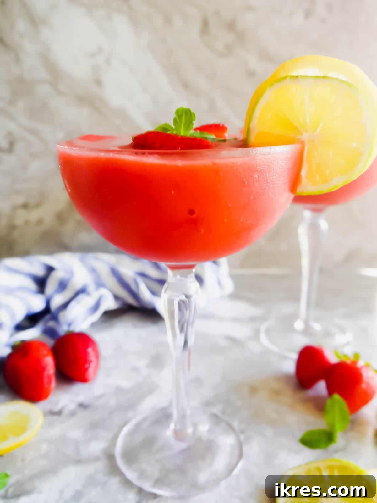 The side angle of a healthy strawberry daiquiri recipe in a cocktail glass, showcasing its vibrant red color and icy texture.