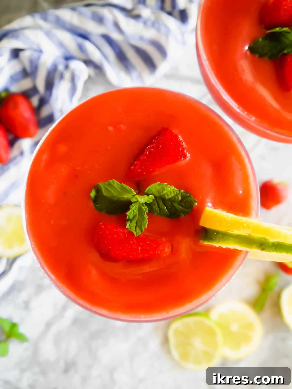 Aerial view of a healthy strawberry daiquiri in a glass, with a garnish of mint and a strawberry.