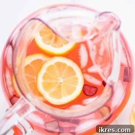 A glass of refreshing Rhubarb Lemonade with ice and lemon slices.