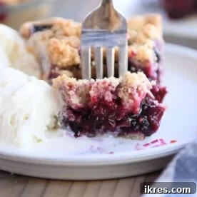 A slice of Triple Berry Rhubarb Pie with a generous streusel topping.