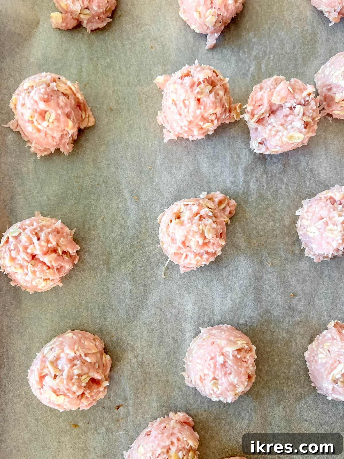 Raw, formed turkey meatballs neatly arranged on a parchment-lined baking sheet, ready for baking.