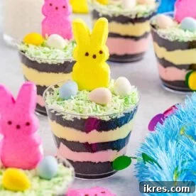 Individual Easter dirt cups featuring layers of Oreo crumbs and pudding, topped with colorful edible Easter decorations.