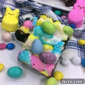 A tray of chocolate brownies topped with colorful Peeps, Cadbury eggs, and M&M eggs, creating a festive Easter dessert.
