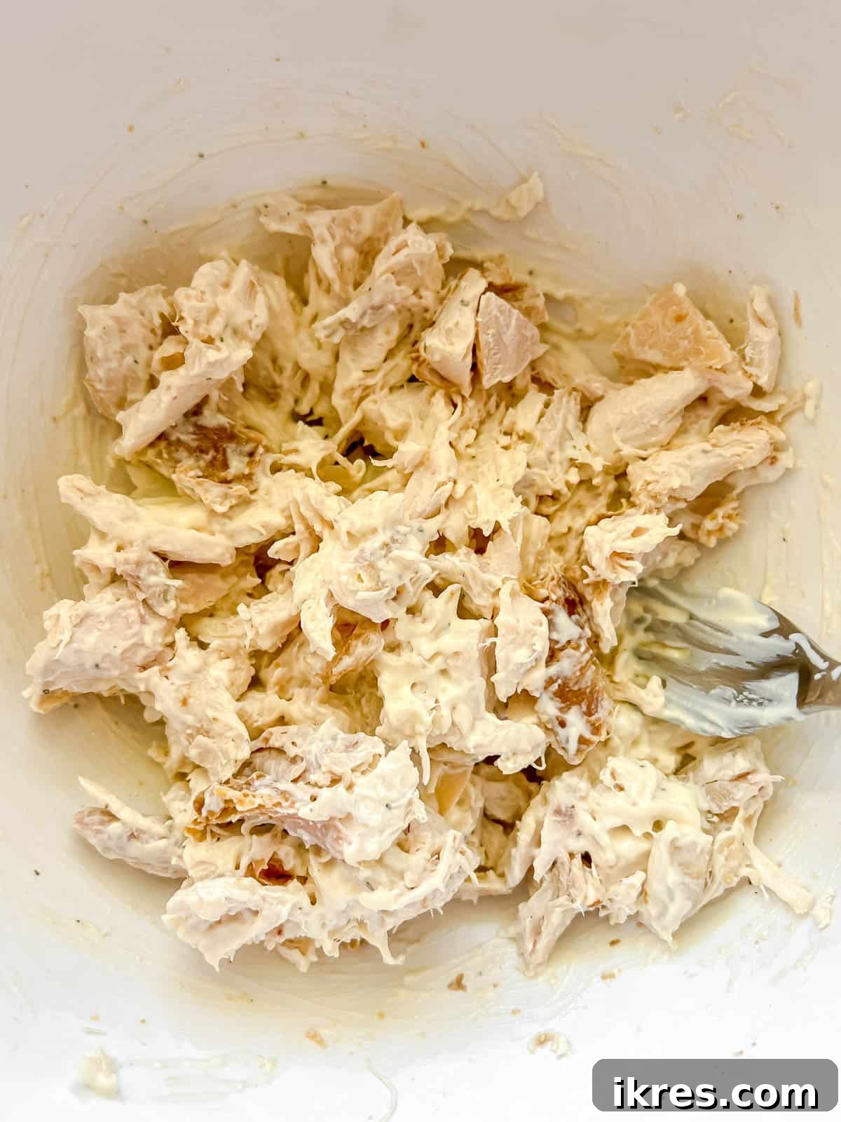Speedy Rotisserie Chicken Salad Lettuce Cups 6 Mayonnaise sauce being mixed into the prepared chicken, ensuring even coating.