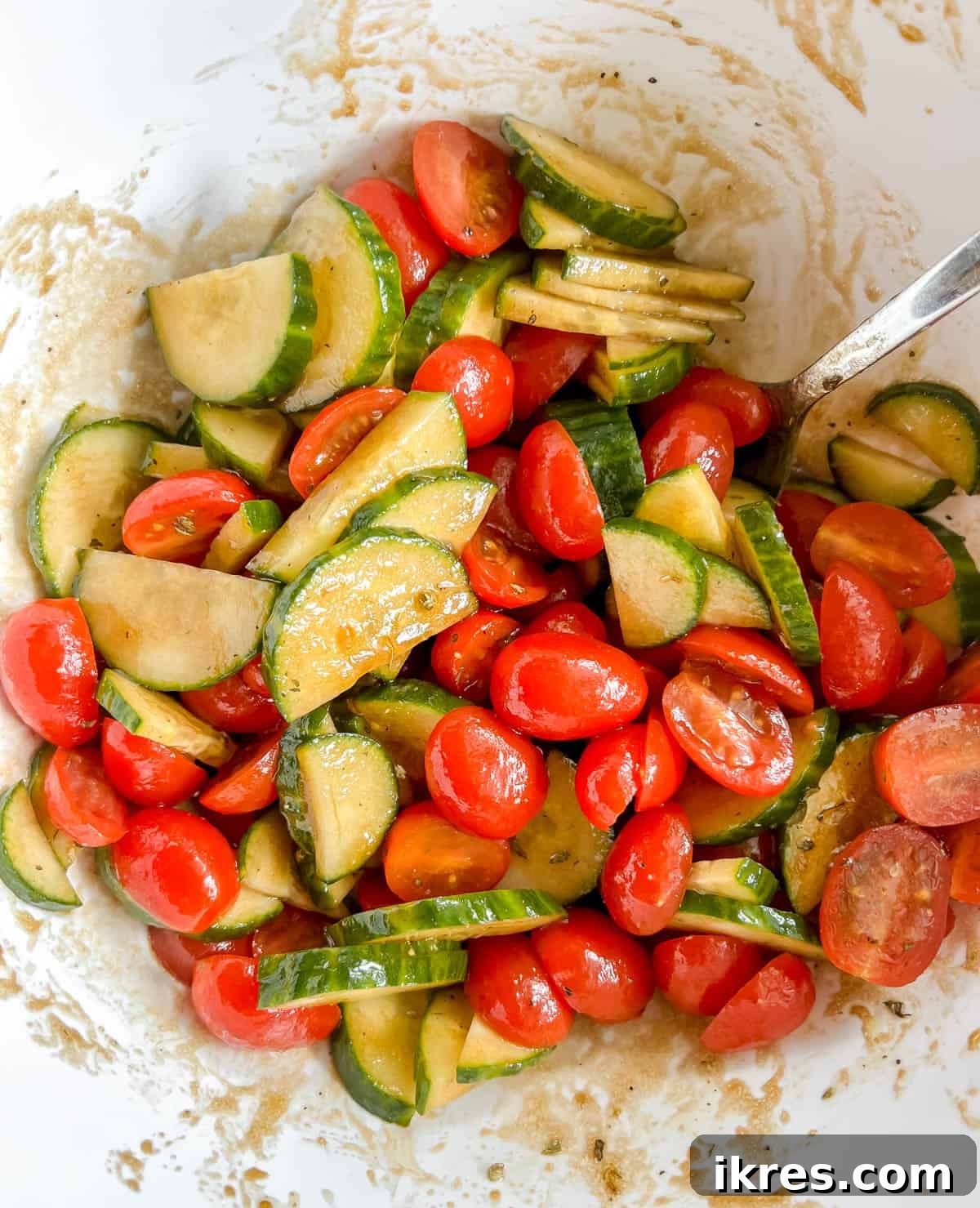 Vibrant Avocado Goat Cheese Salad with Balsamic Drizzle 5 Mixing balsamic dressing with tomato and cucumber salad in a bowl.