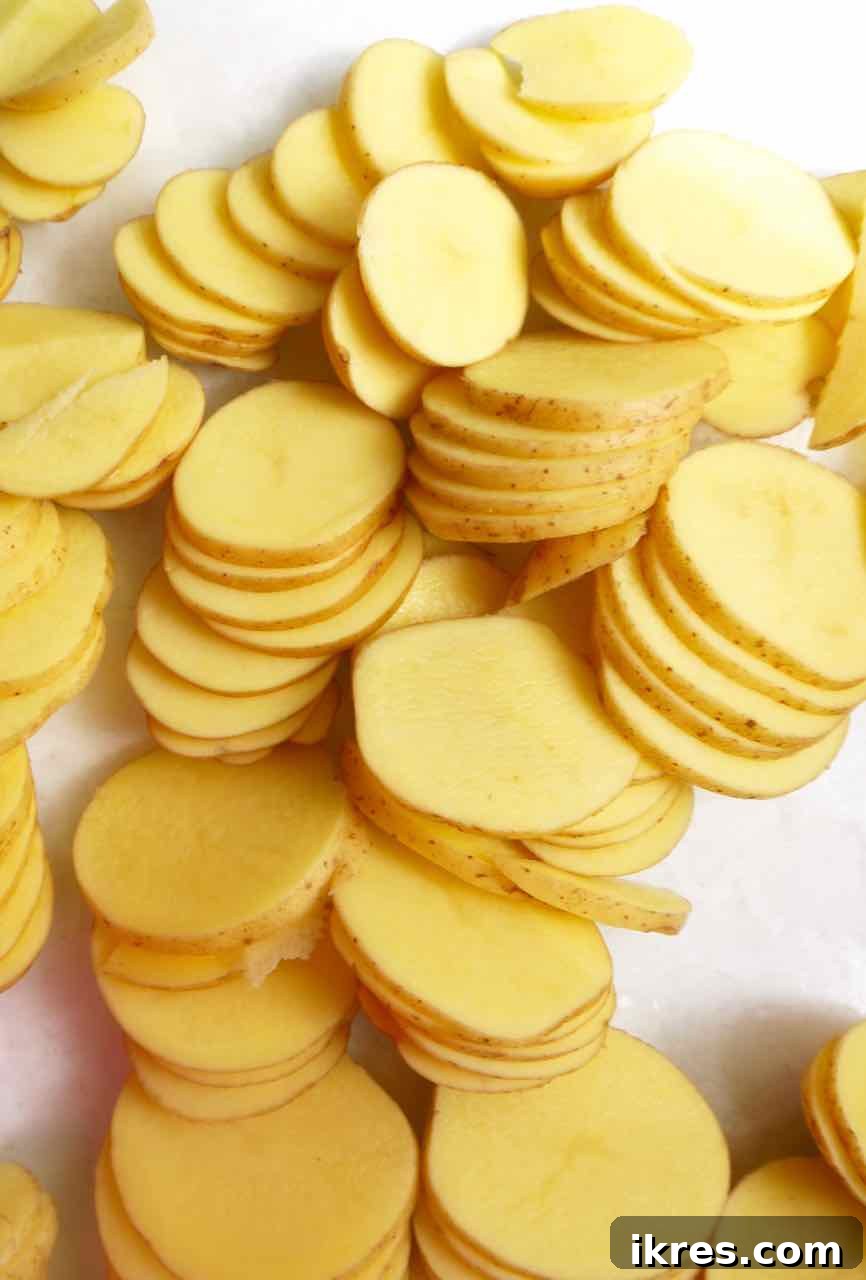 Creamy Dairy Free Scalloped Potatoes Paleo Whole30 Gluten Free 5 Thinly sliced raw potatoes neatly arranged for the scalloped potatoes recipe prep.