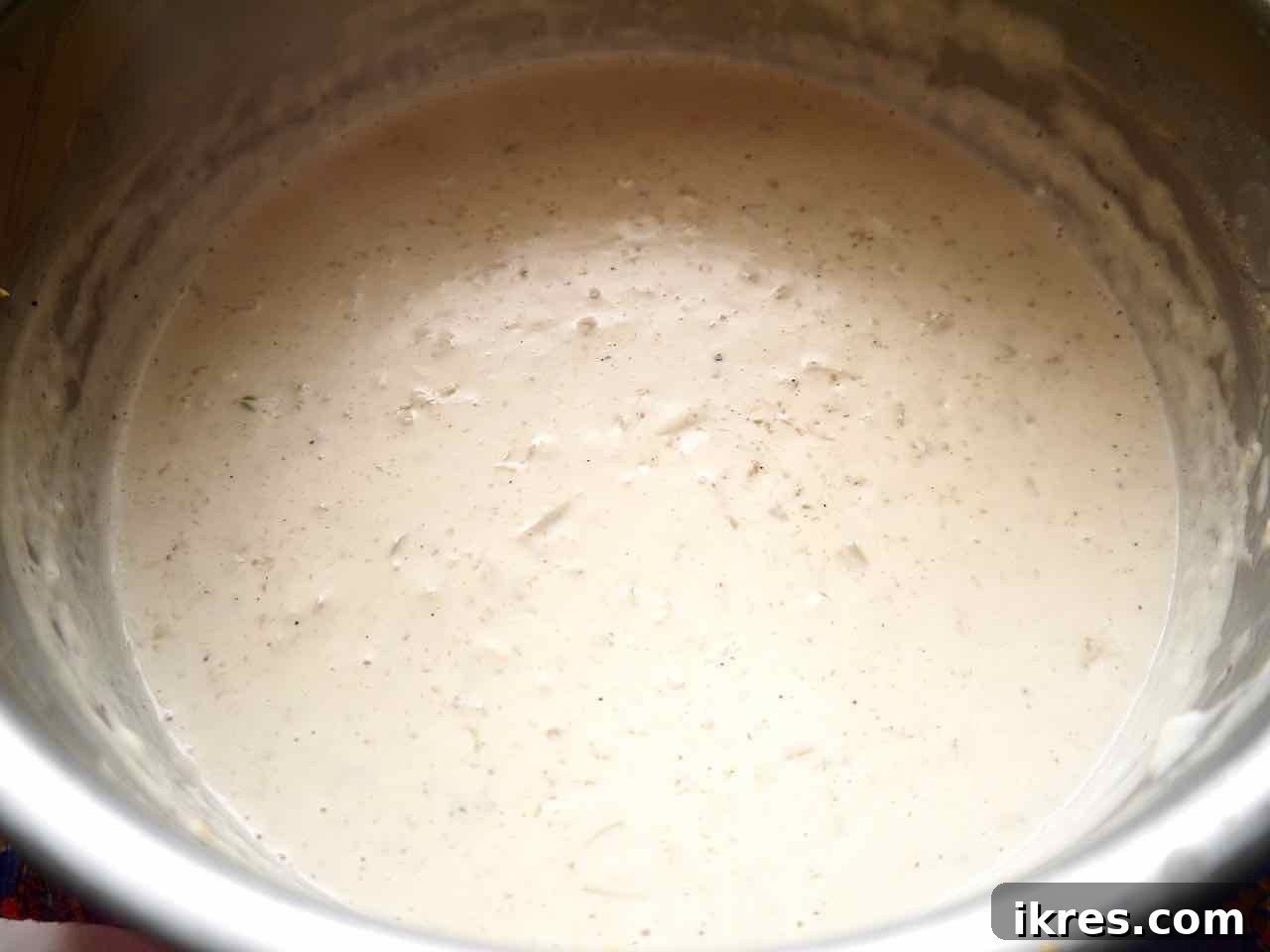 Creamy Dairy Free Scalloped Potatoes Paleo Whole30 Gluten Free 6 Dairy-free béchamel sauce simmering in a saucepan with a whisk, showing creamy texture.