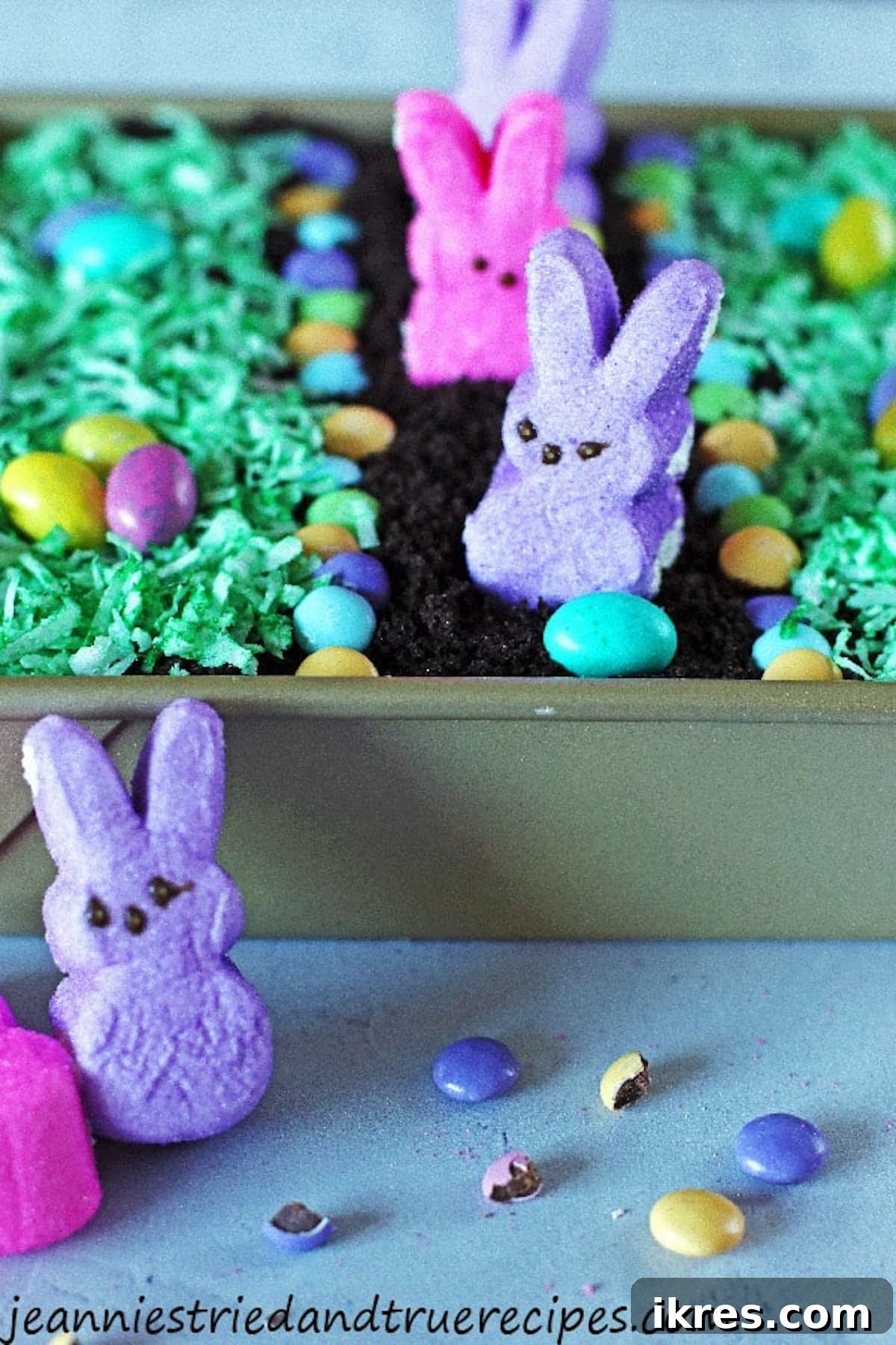 Festive Dirt Cake for Halloween and Easter 11 An adorable Easter Dirt Cake adorned with colorful Peep bunnies and an assortment of candy eggs. The cake is blanketed with bright green shredded coconut, simulating lush grass for a festive spring display.