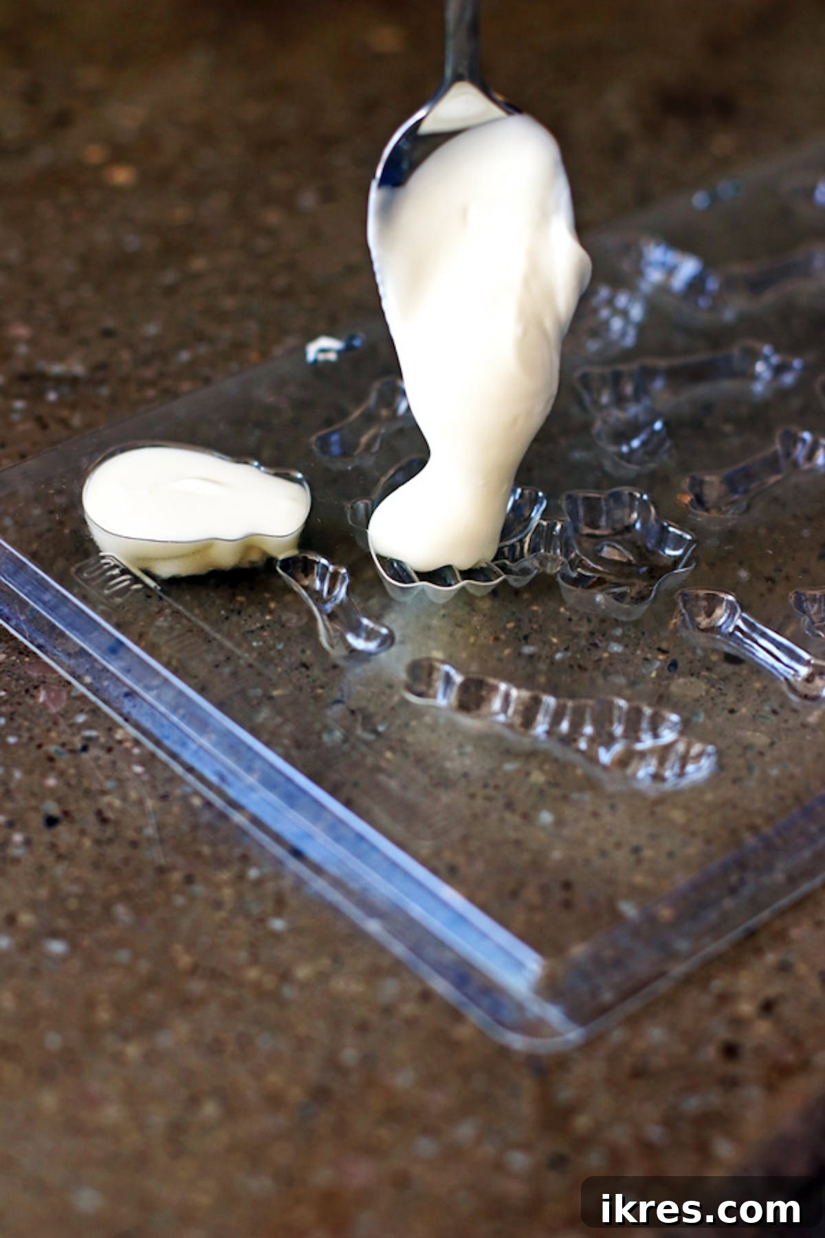Festive Dirt Cake for Halloween and Easter 7 Melted white chocolate being carefully poured into a skeleton-shaped candy mold using a spoon, a key step in creating the edible skeleton decoration for the Halloween Dirt Cake.