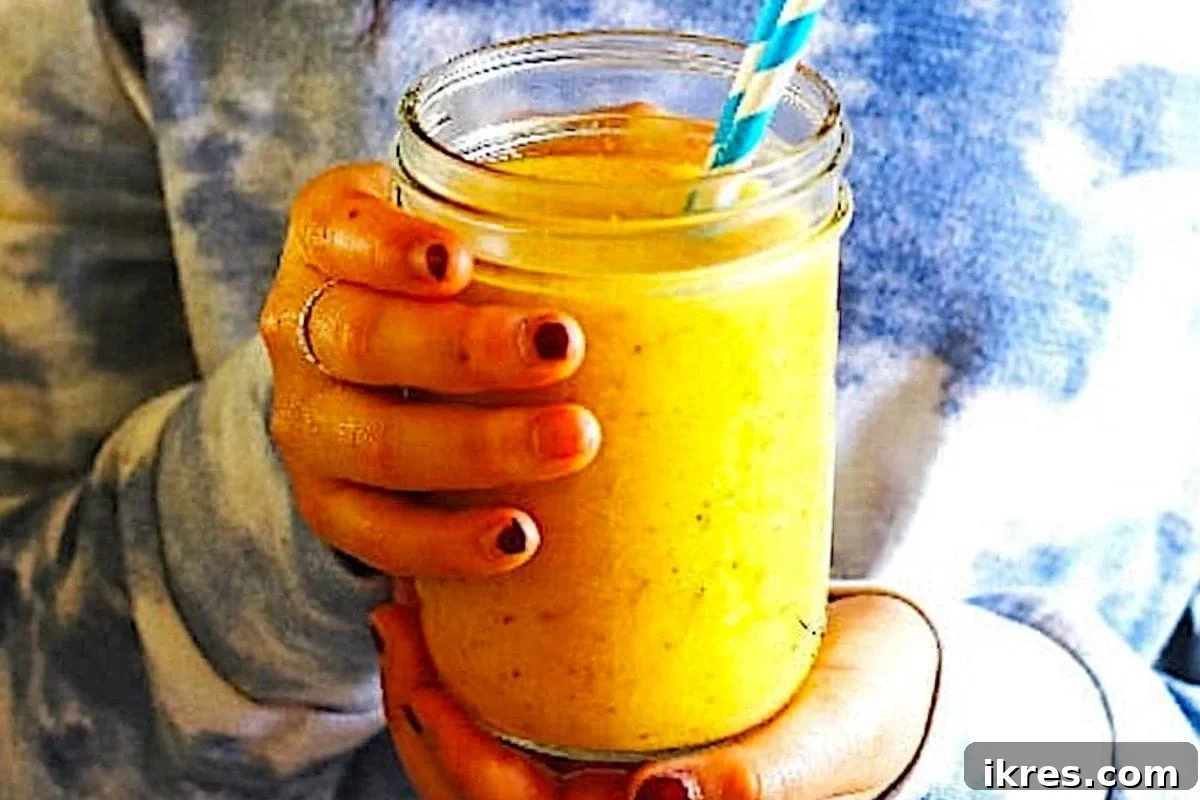 A glass of tropical pineapple mango smoothie with a slice of pineapple.