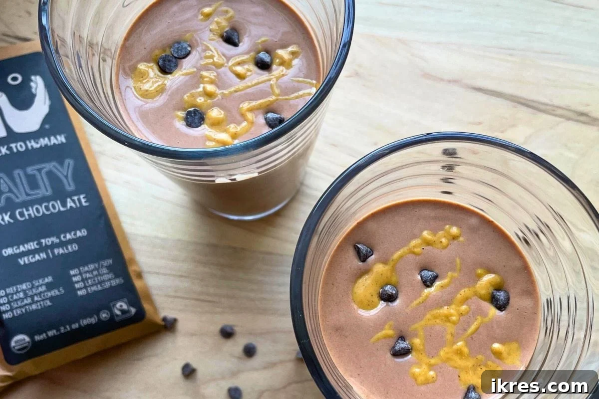 Two chocolate, peanut butter, and banana smoothies with peanut butter drizzled over the top.