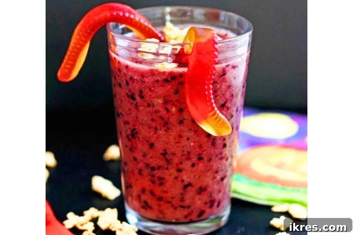 A vibrant purple smoothie in a glass with a straw, garnished with gummy worms.