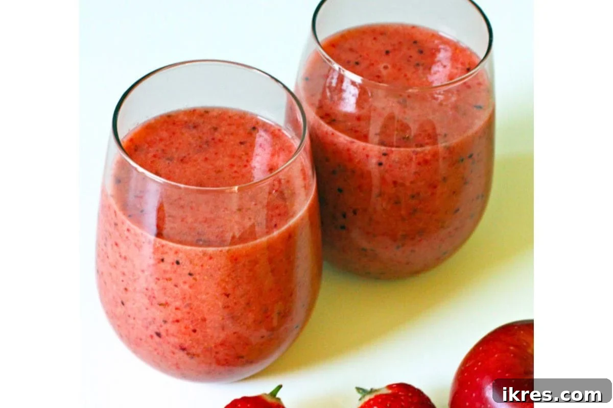 A glass of strawberry kiwi smoothie garnished with fresh kiwi slices.
