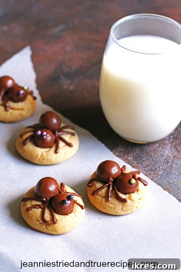 A delightful arrangement of decorated peanut butter spider cookies next to a tall glass of milk, perfect for a Halloween treat.