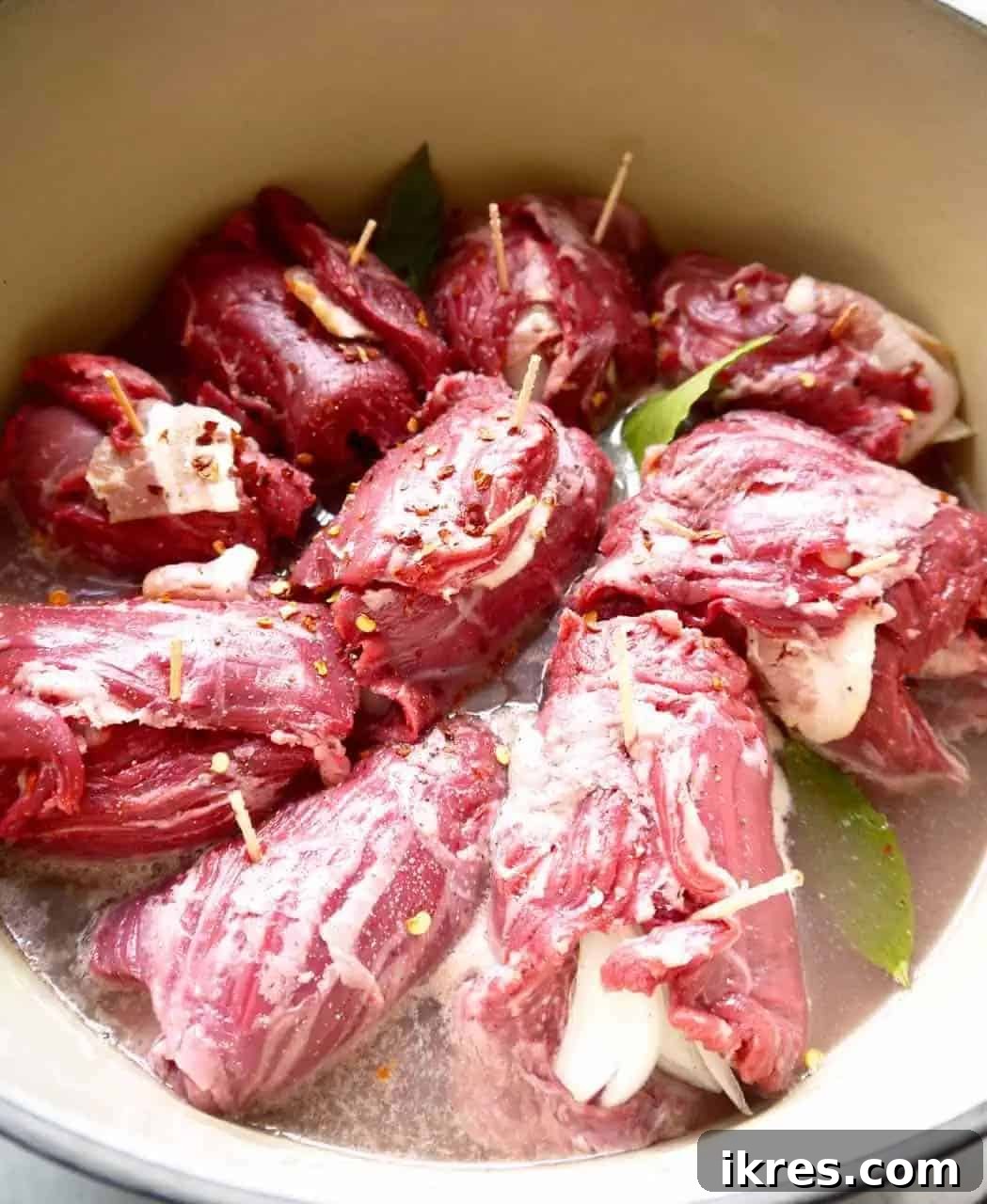 Beef Roulade Stuffed with Smoky Bacon, Sweet Onion, and Fresh Thyme 6 Beef roulades with bacon and onion simmering in a Dutch oven with liquid and herbs.