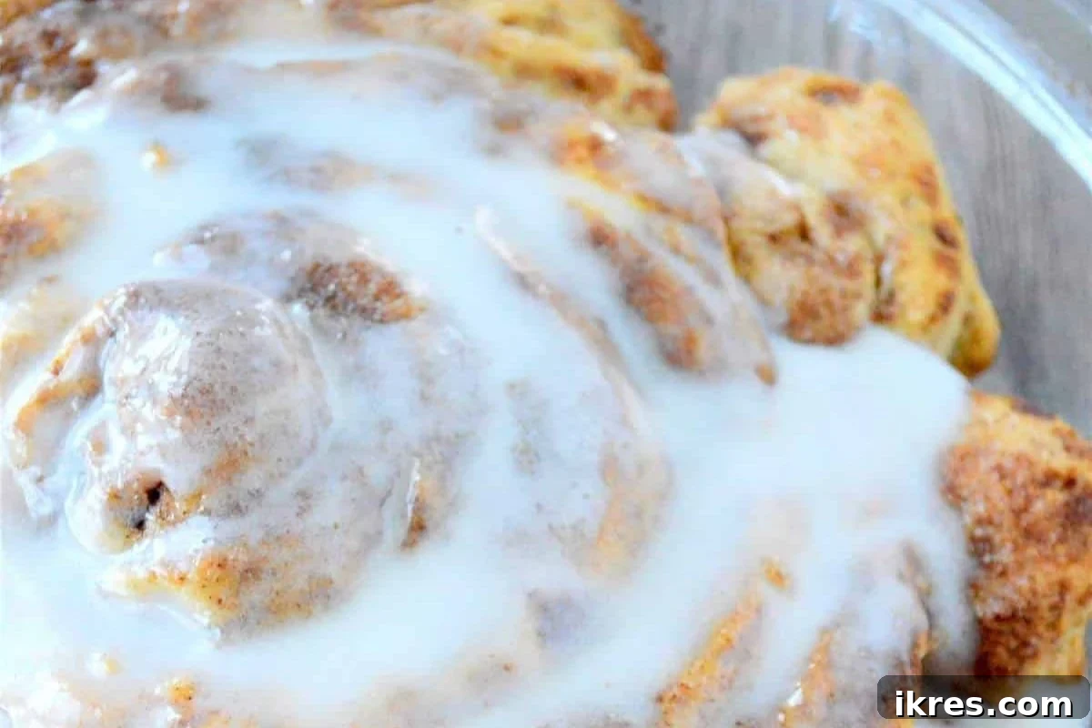 A massive, perfectly baked fluffy cinnamon roll generously slathered with sweet cream cheese frosting, prepared quickly for a special breakfast.