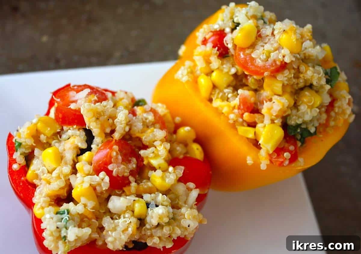 Comforting Crockpot Stuffed Peppers 6 Two perfectly stuffed quinoa and veggie bell peppers on a white plate, ready for the slow cooker.