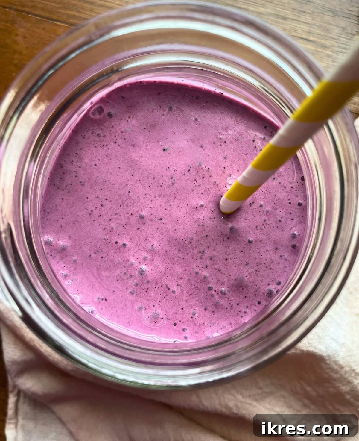 Vibrant Blueberry Pineapple Blast 12 A creamy blueberry smoothie with pineapple, banana, yogurt, and a hint of spinach, served in a mason jar with a yellow and white striped straw, viewed from the top to show its rich texture.