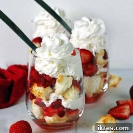 Two angel food cake strawberry shortcakes in stemless wine glasses topped with whipped cream.