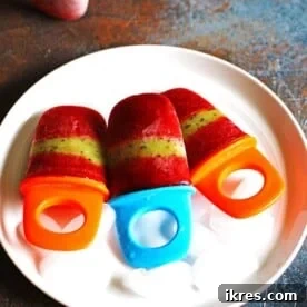 Strawberry Kiwi Popsicles on a white plate sitting on a multi-colored counter