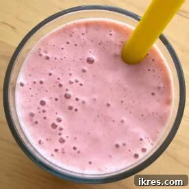 A close-up of a strawberry banana smoothie with Greek yogurt with a yellow straw.