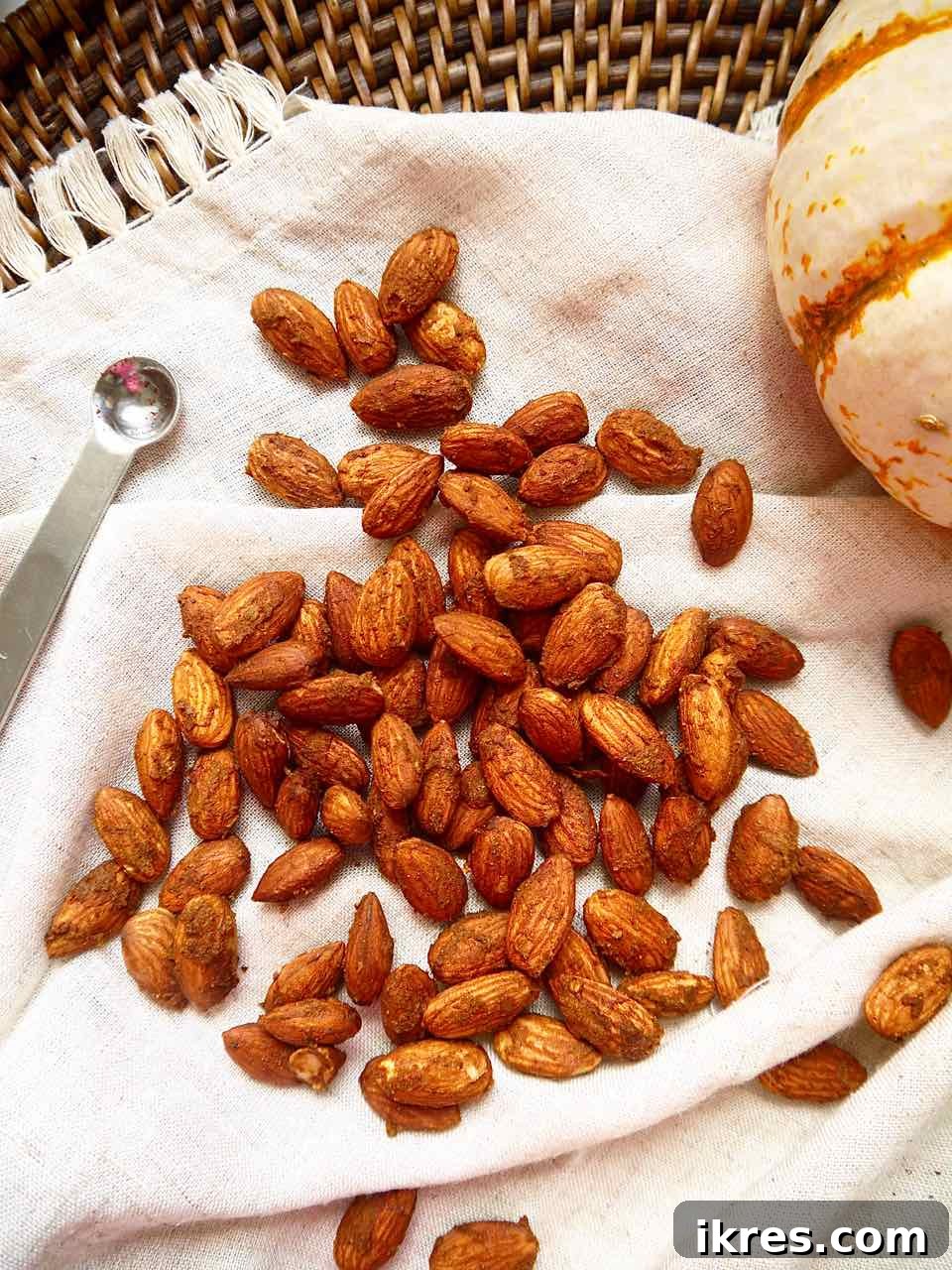 Close-up of perfectly roasted pumpkin spice almonds arranged artfully on a white napkin, emphasizing their perfect coating and appealing golden-brown color.