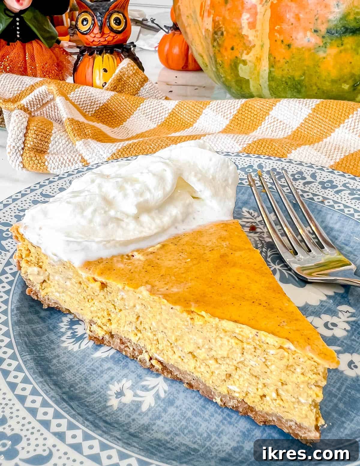 Gingersnap Crusted Pumpkin Cheesecake 2 A beautiful slice of Pumpkin Cheesecake with a Gingersnap Graham Cracker Crust, elegantly presented on a white plate, garnished with whipped cream and a sprinkle of cinnamon.