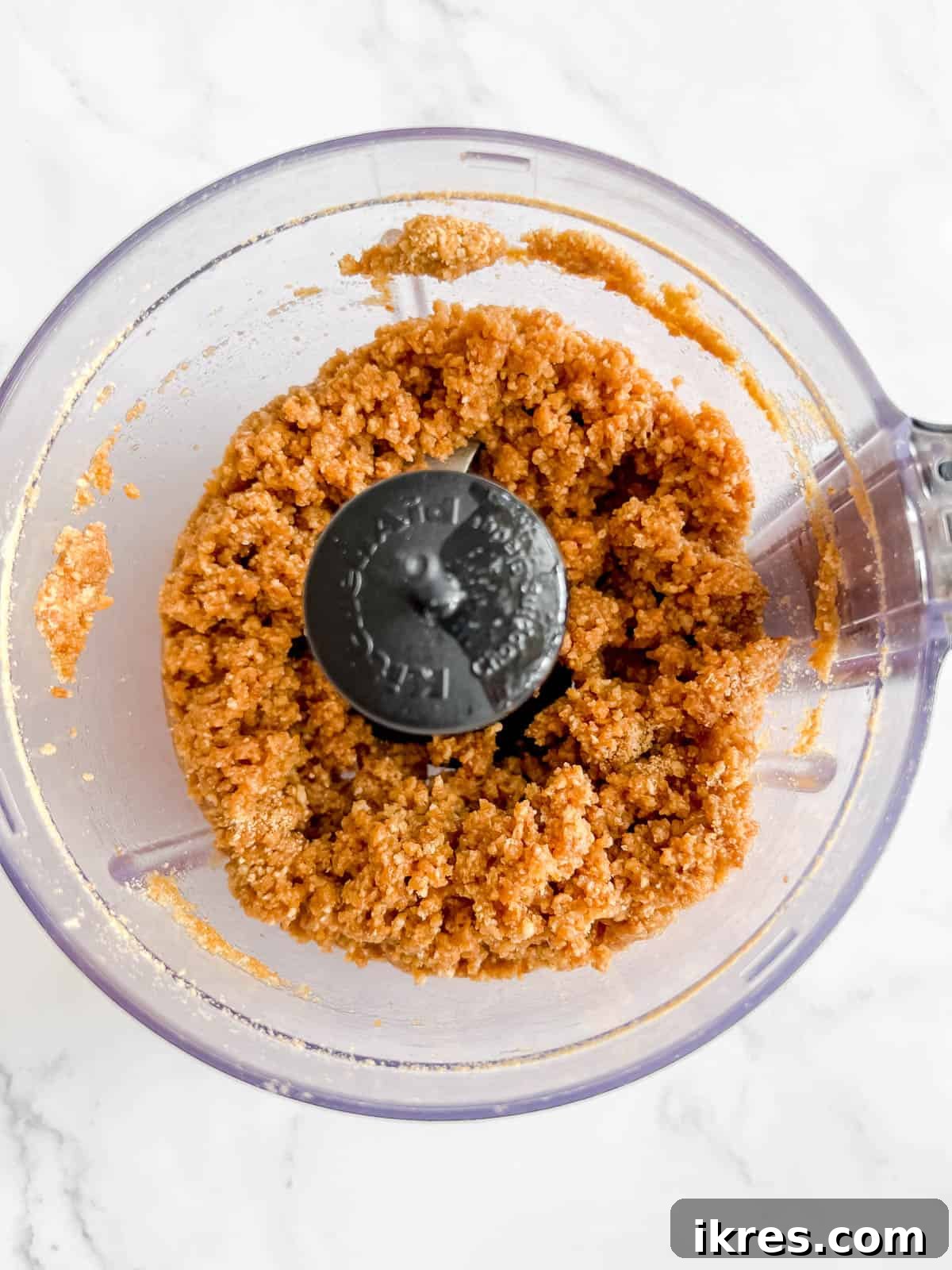 Gingersnap Crusted Pumpkin Cheesecake 4 Gingersnap and graham cracker crumbs being processed in a food processor, forming a crumbly mixture for the cheesecake crust.