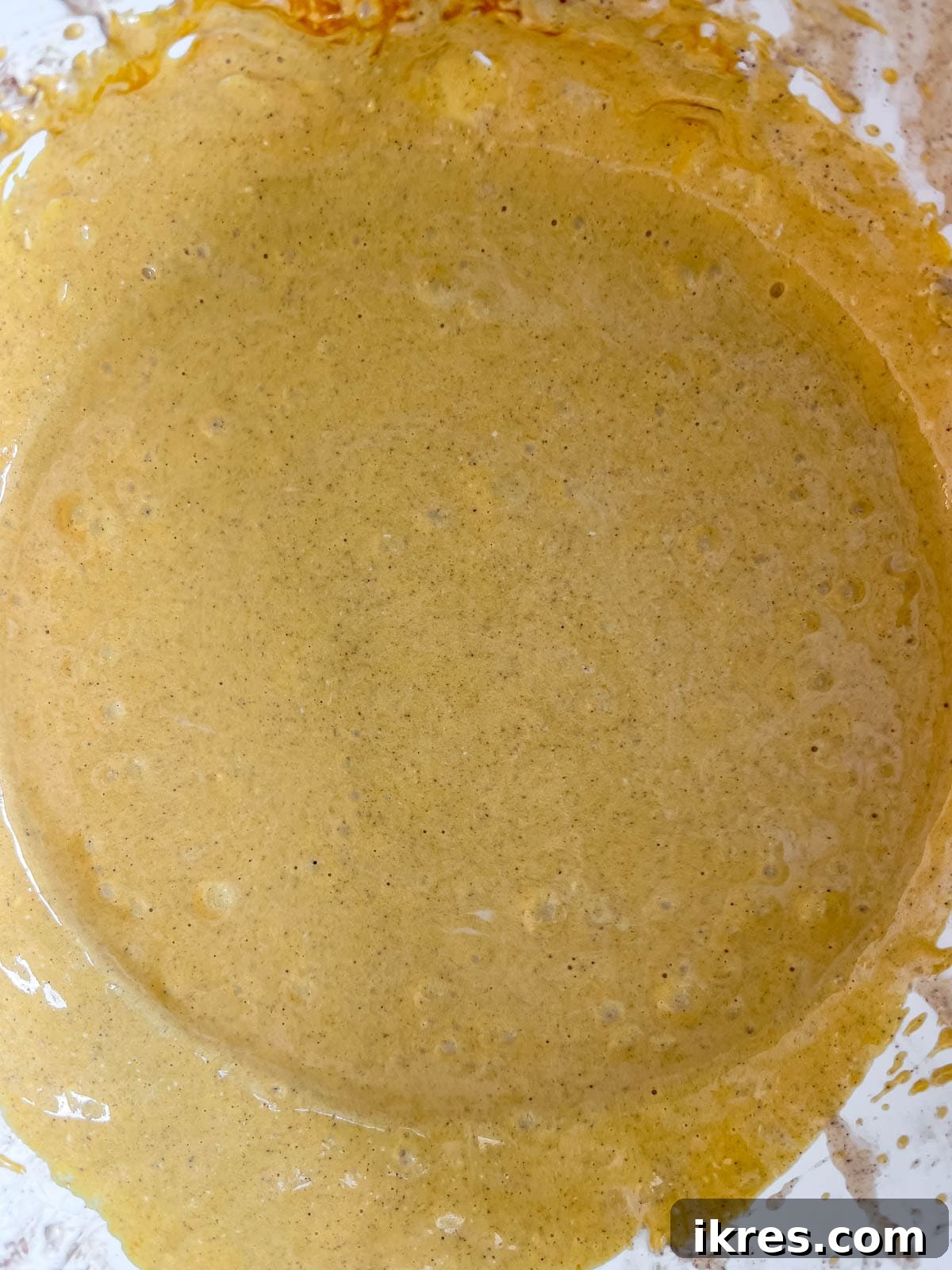 Gingersnap Crusted Pumpkin Cheesecake 9 Pumpkin puree being added and mixed into the cheesecake batter.