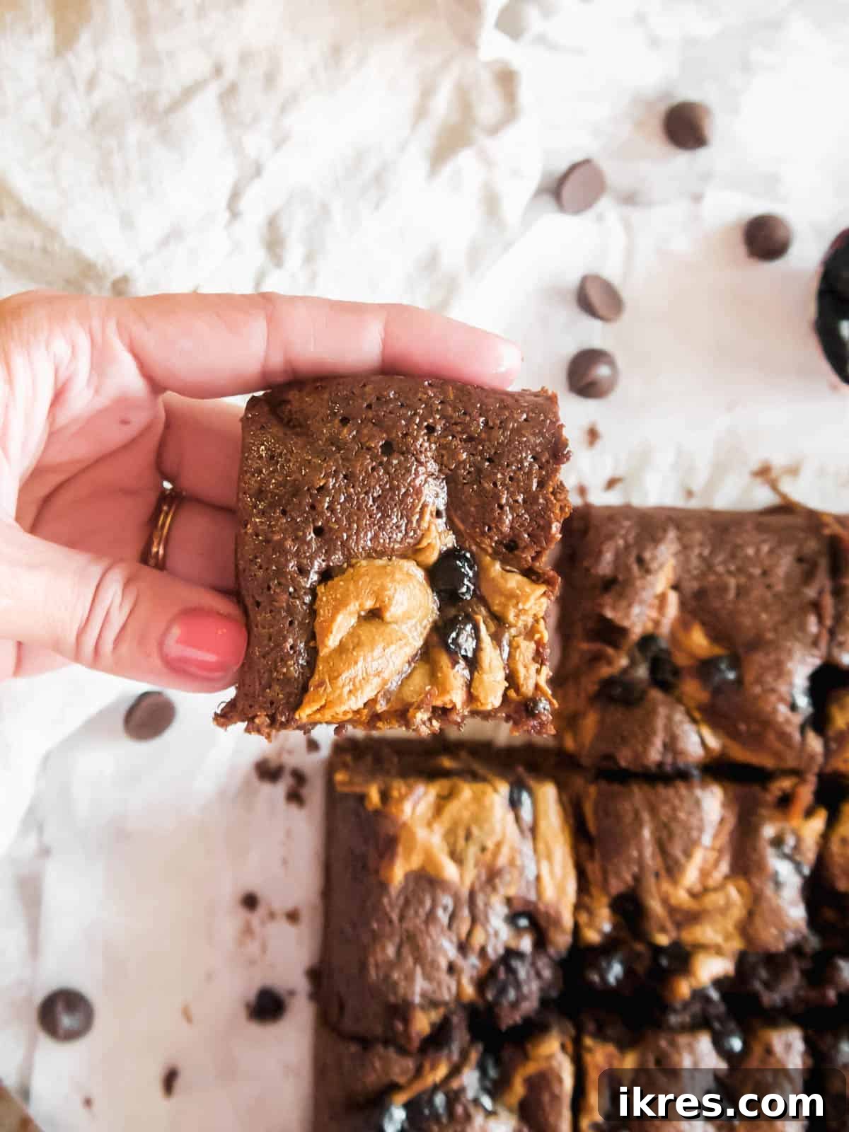 Lifting a fudgy slice of the best Paleo brownies, showing the rich chocolate and swirls of almond butter and jelly.