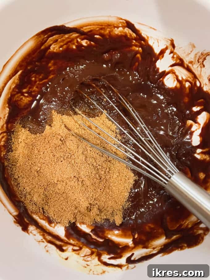 Adding vanilla extract and coconut sugar to the warm, melted chocolate mixture.