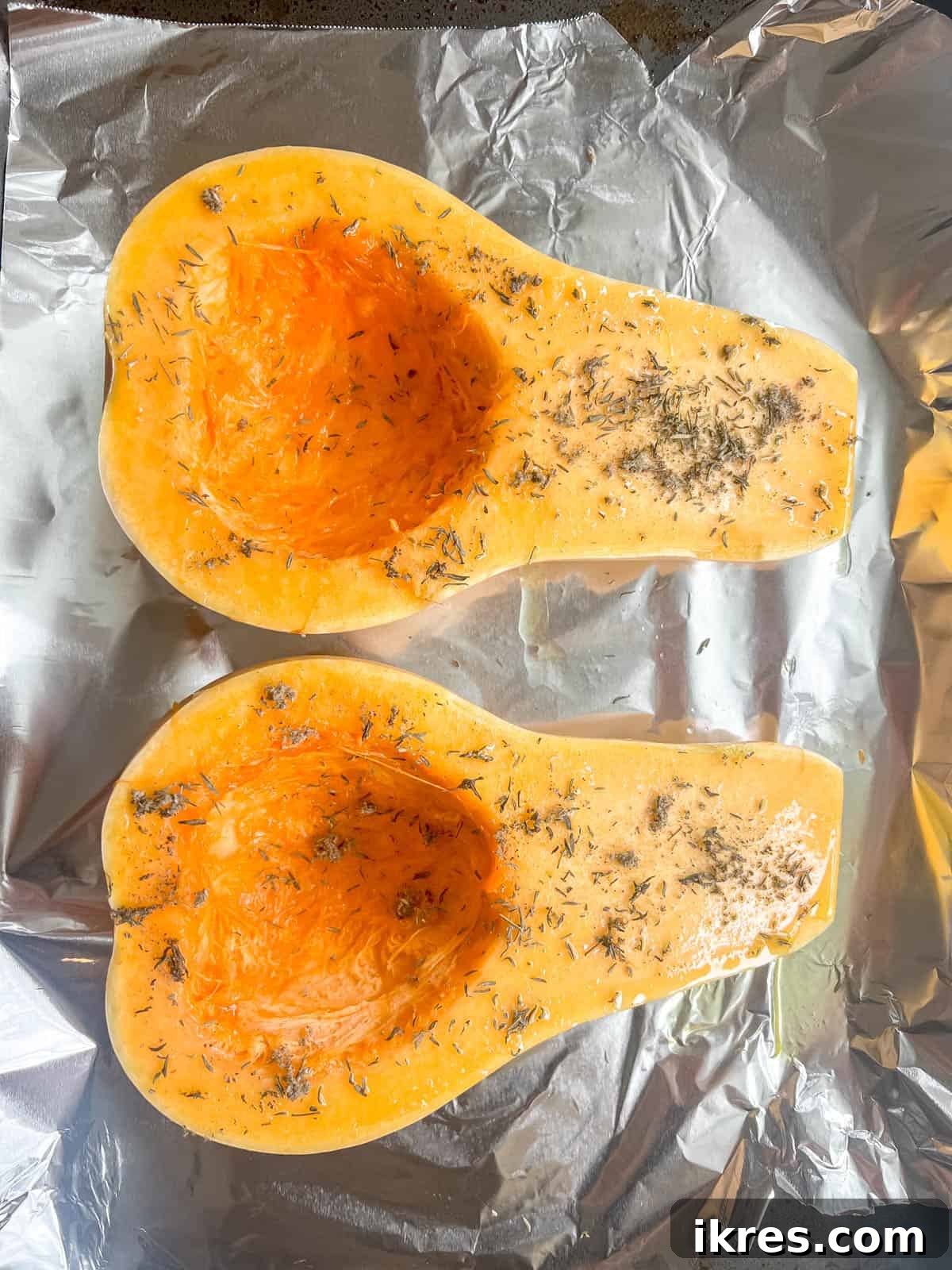 Golden Butternut Cloud 4 Butternut squash halves, with seeds removed, brushed with olive oil, rubbed sage, and dried thyme, ready to be placed in the oven for roasting.