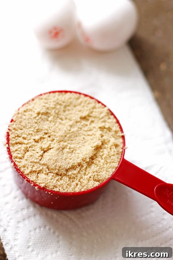 Decadent Cookie Squares 5 Brown sugar packed into a red measuring cup, demonstrating the correct measurement technique.