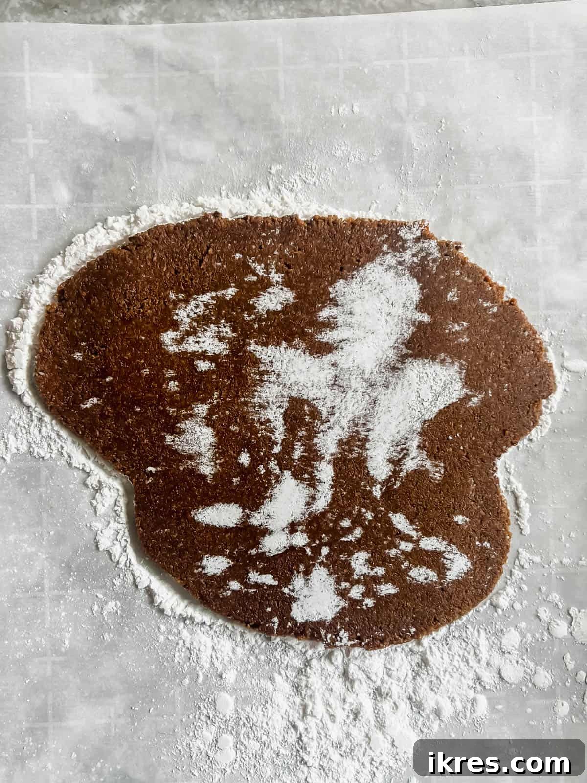 Rolled out gingerbread dough on parchment paper.