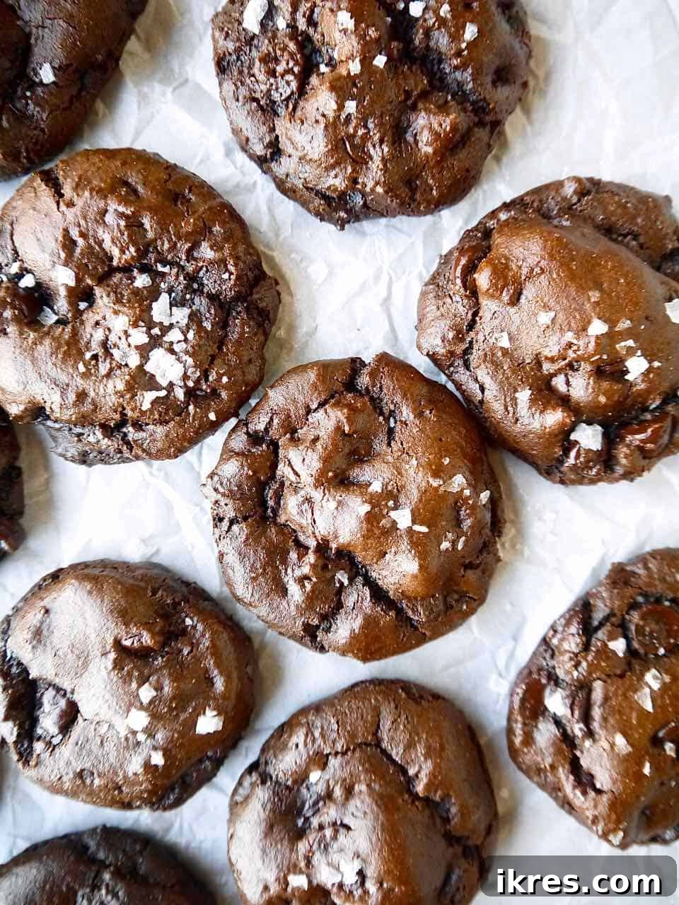 Decadent Paleo Gluten-Free Double Chocolate Chip Cookies 3 Freshly baked paleo chocolate cookies cooling on parchment paper on a wire rack, sprinkled with sea salt.