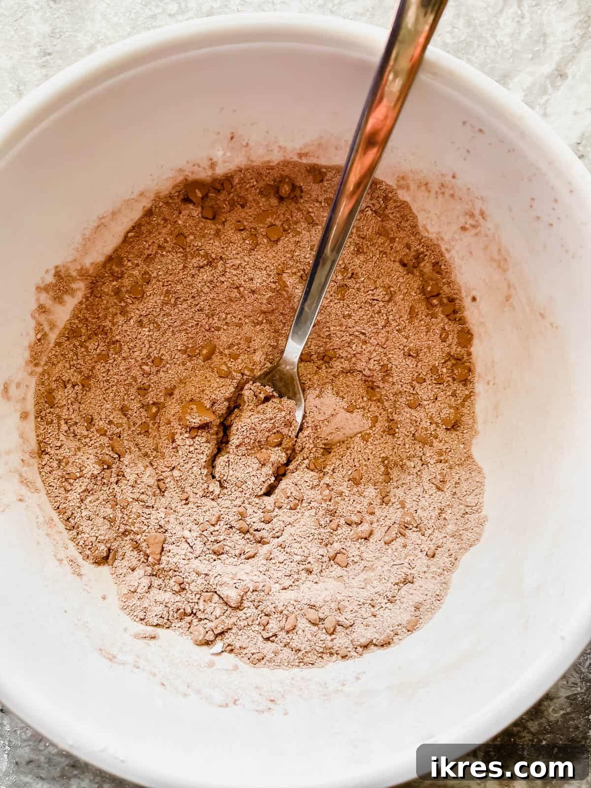 Decadent Paleo Gluten-Free Double Chocolate Chip Cookies 5 A bowl containing a mixture of dry ingredients for baking, including various flours, cocoa, and leavening agents.