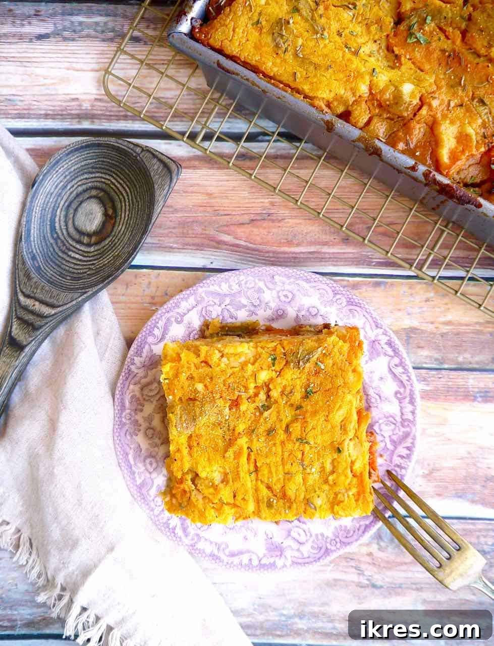 A close-up of a perfectly portioned serving of Butternut Squash Shepherd's Pie on a plate, highlighting the creamy, golden topping and the rich, savory meat filling underneath, often garnished with a sprig of fresh thyme or parsley.