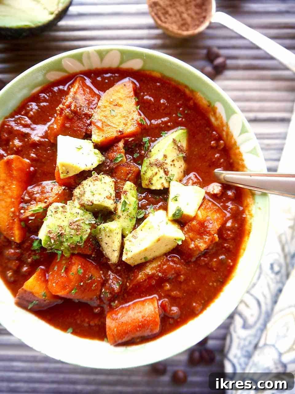 Cocoa powder in chili in a bowl, garnished with fresh cilantro.