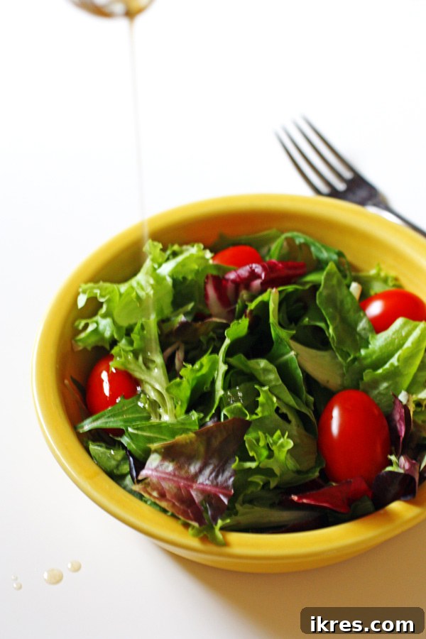 Easy Homemade Balsamic Vinaigrette 3 Balsamic Vinaigrette being poured from a glass cruet onto a fresh green salad.