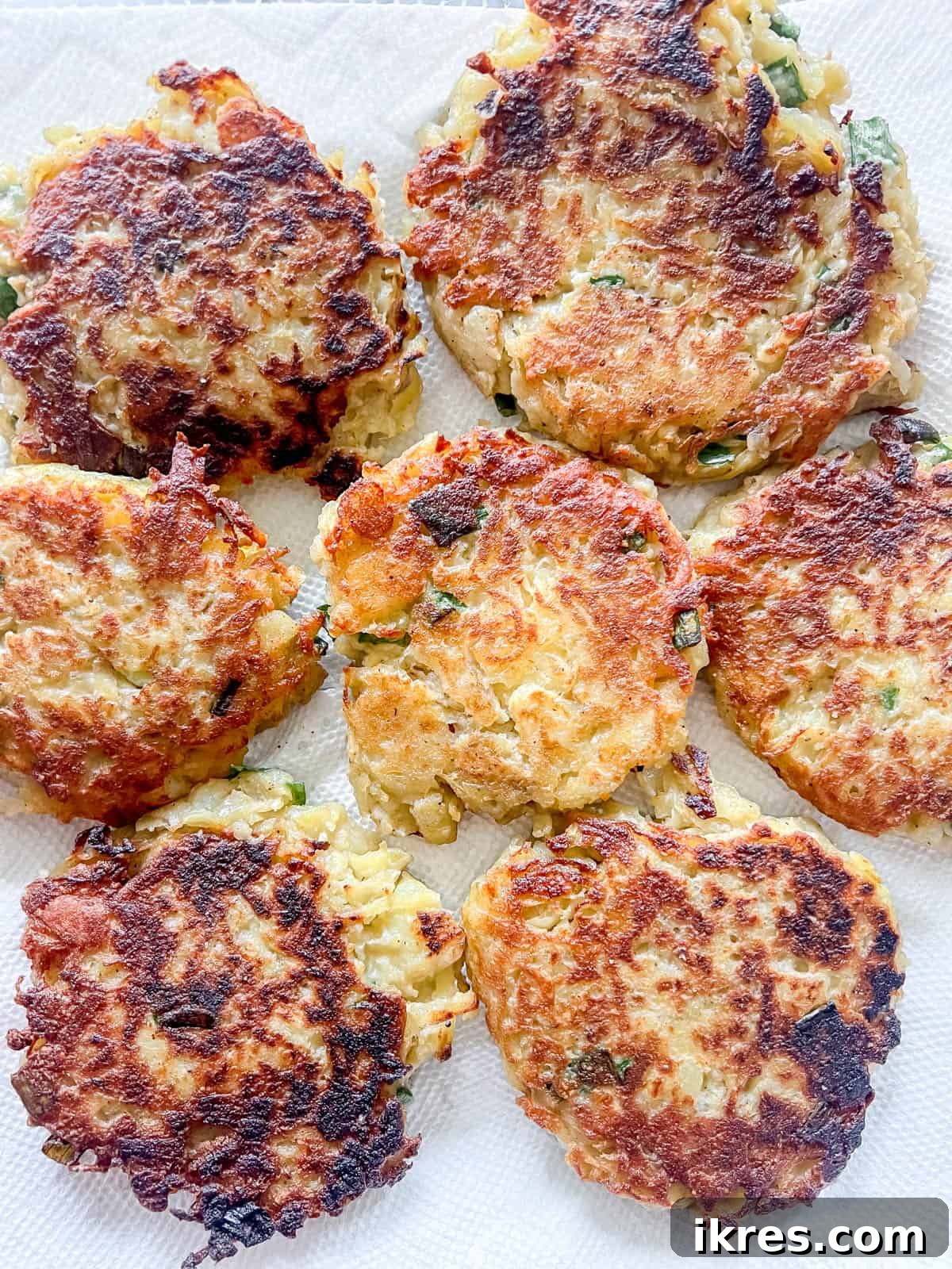 Freshly cooked, golden potato pancakes are placed on paper towels to absorb any excess oil, ready for serving.